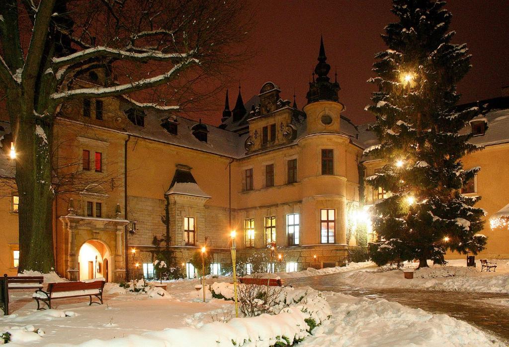 Snow-covered castle courtyard illuminated at night with festive lights.