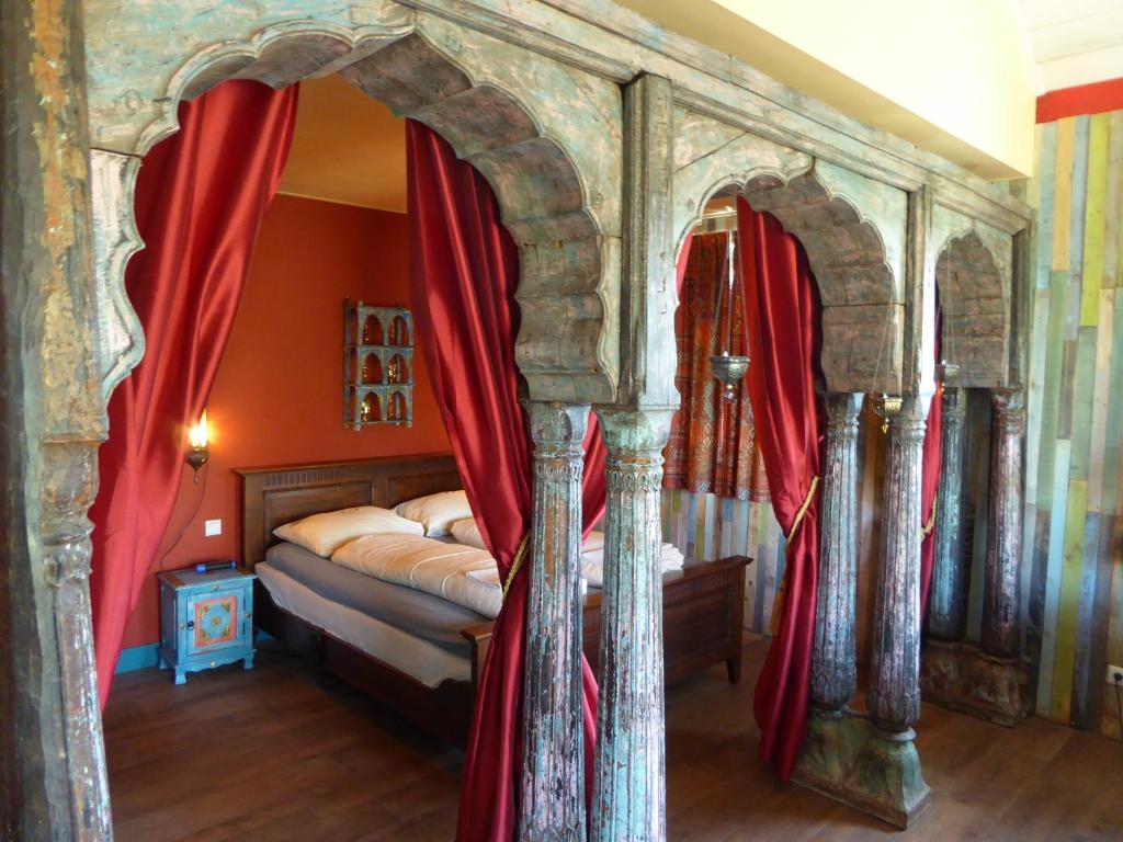 a bedroom with a canopy bed with red curtains at Vakantiewoning 1001 Nacht in Welsum