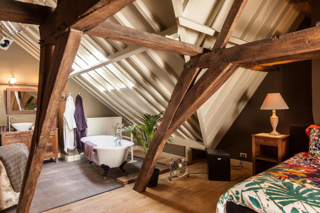 a attic room with a bath tub and a bed at B&B Door 10 in Ghent