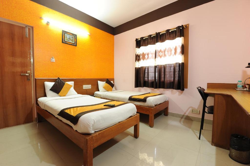 Habitación con 2 camas y escritorio. en Arra Transit Bengaluru International Airport Hotel en Yelahanka