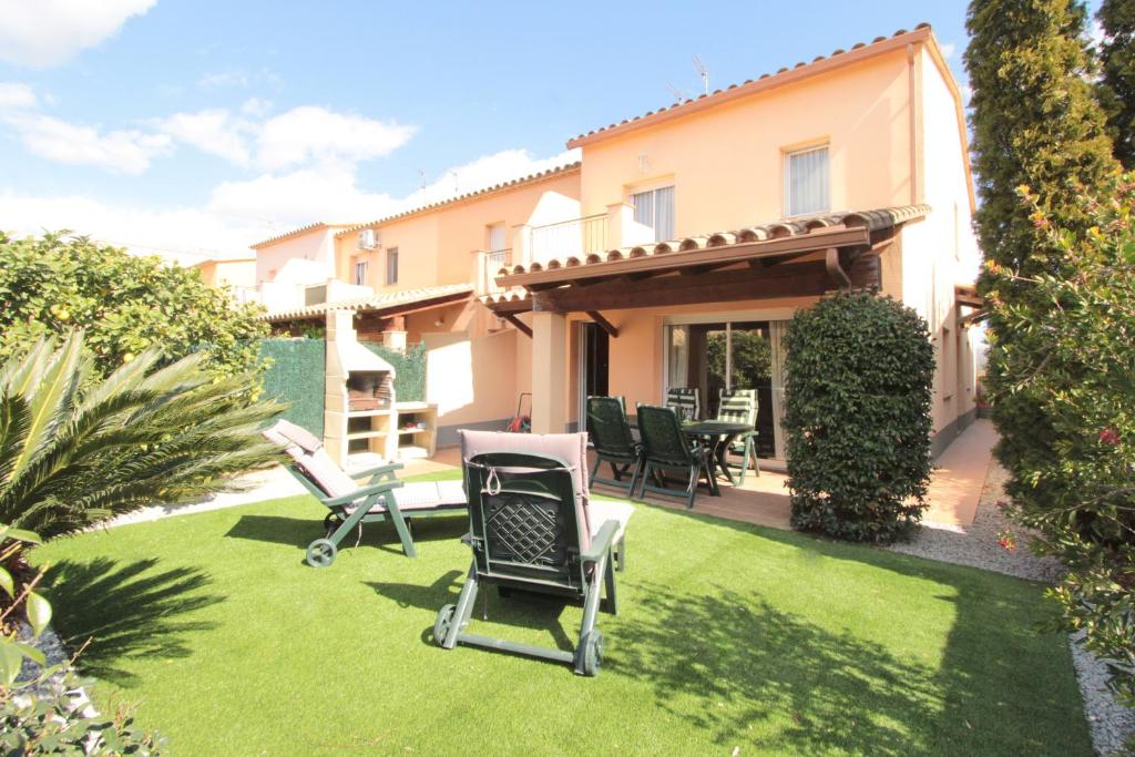 a backyard with chairs and a table on a lawn at LEON INMO Chalet Arenal - 15687 in Castelló d'Empúries