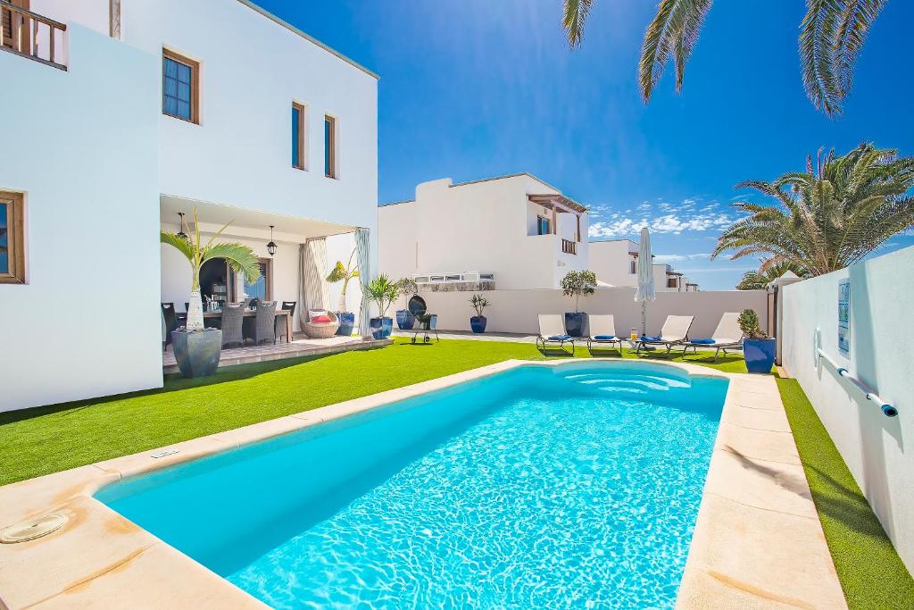 a villa with a swimming pool in front of a house at Las Caletas Village in Costa Teguise