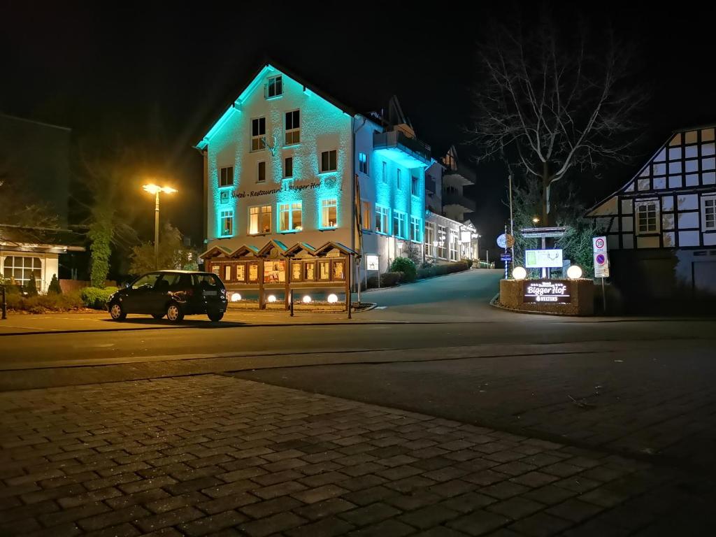 un coche aparcado frente a una casa con luces azules en Hotel Bigger Hof - Wirtshaus Platzhirsch am Jahnplatz, en Olsberg