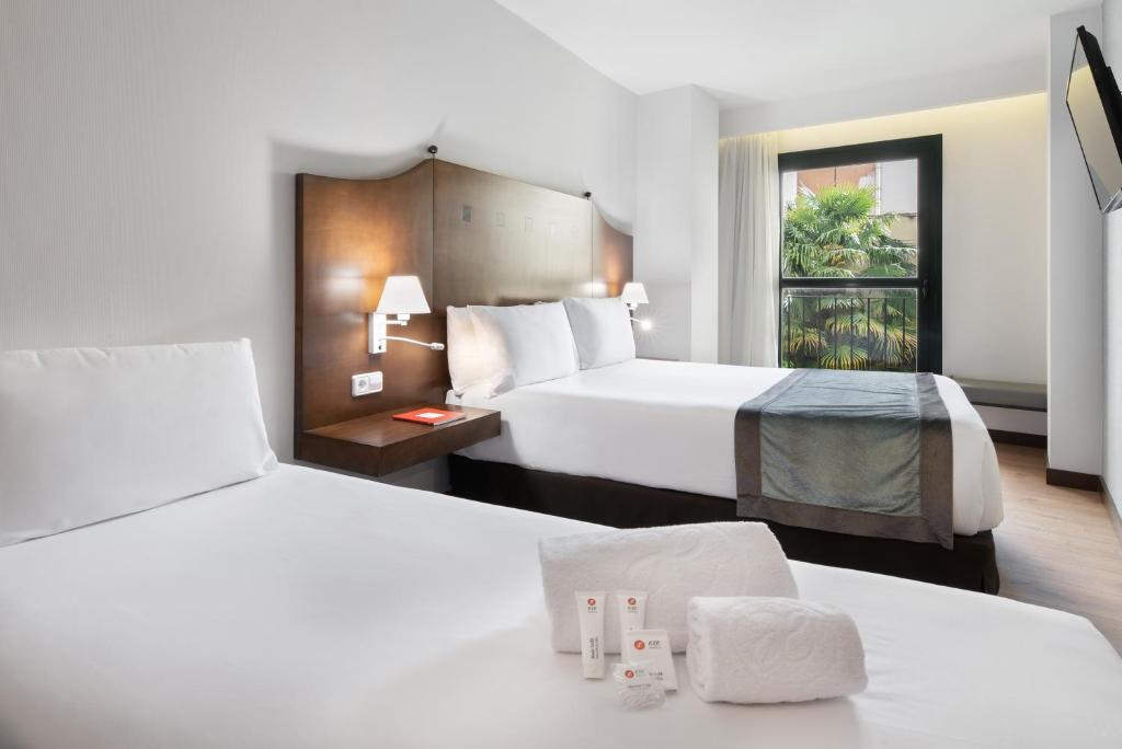 um quarto de hotel com duas camas e uma janela em Exe Agora Cáceres em Cáceres