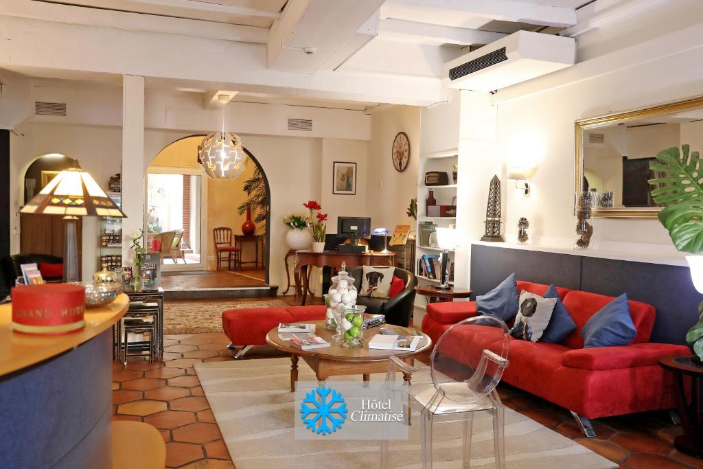 una sala de estar con sofás rojos y una mesa. en Hotel Les Pasteliers en Albi