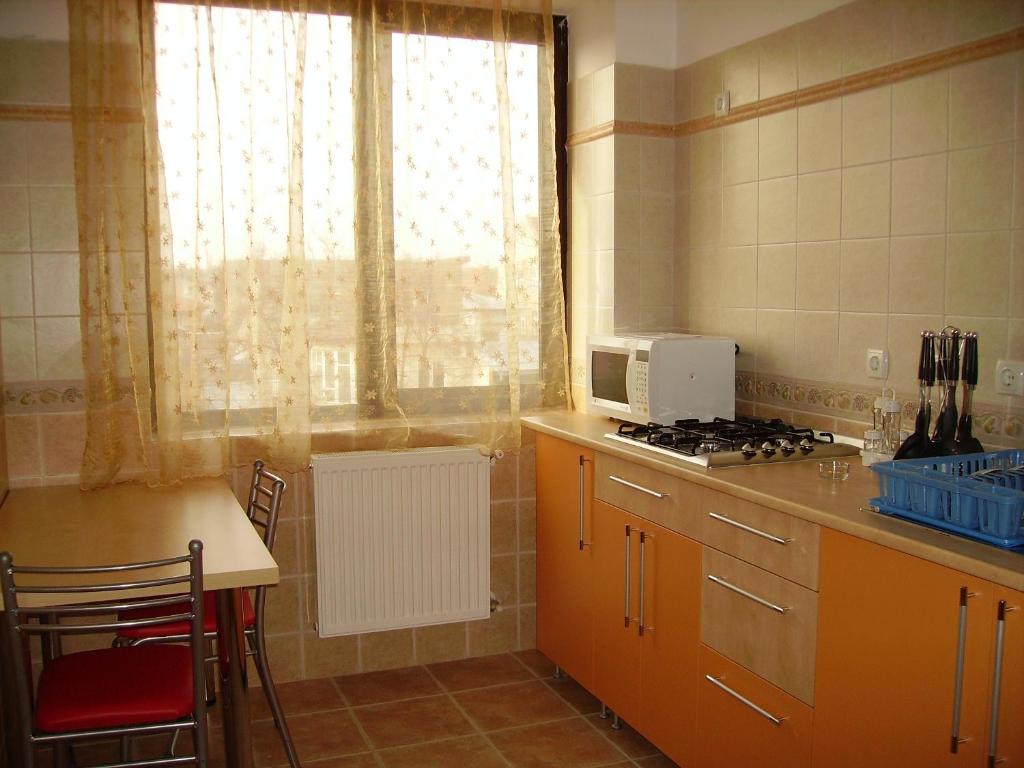 cocina con fogones, ventana y mesa en Villa Edera Residence - Gazda Profesionista, en Bucarest