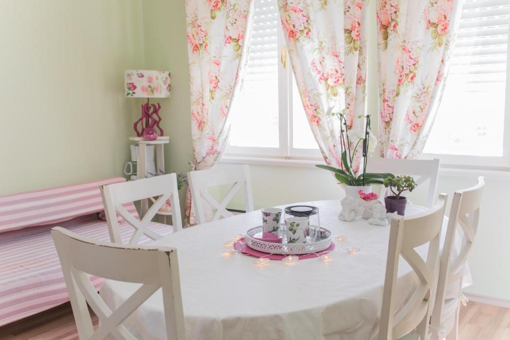 a dining room with a table and chairs with flowers at Shabby Chic Apartments in Šibenik