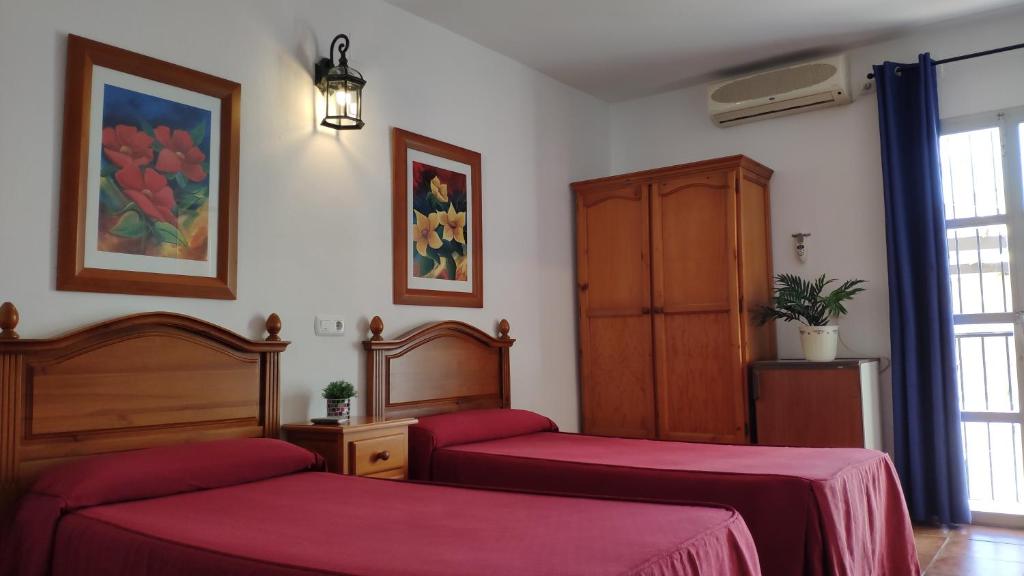 a bedroom with two beds and a cabinet and a window at La Luna in Marbella