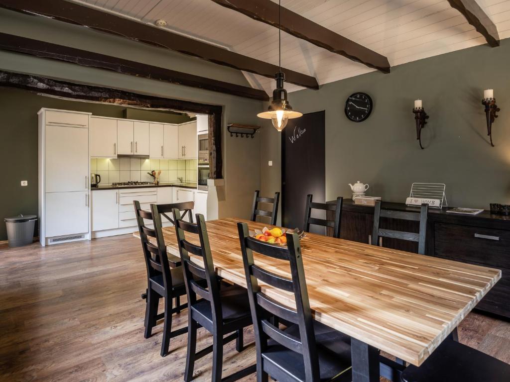 een keuken en eetkamer met een houten tafel en stoelen bij Koetshuis Nunspeet in Nunspeet