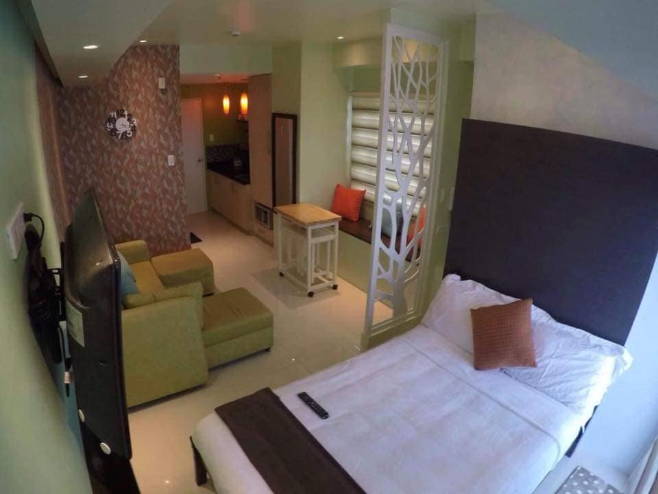 a bedroom with a bed and a living room at 1 Bedroom Unit at SMDC Wind Residences Tagaytay Tower 1 15th floor in Tagaytay