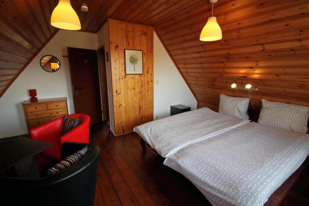 Bed and Breakfast Am Schwatten Berg في Heek: غرفة نوم بسرير ابيض وكرسي احمر