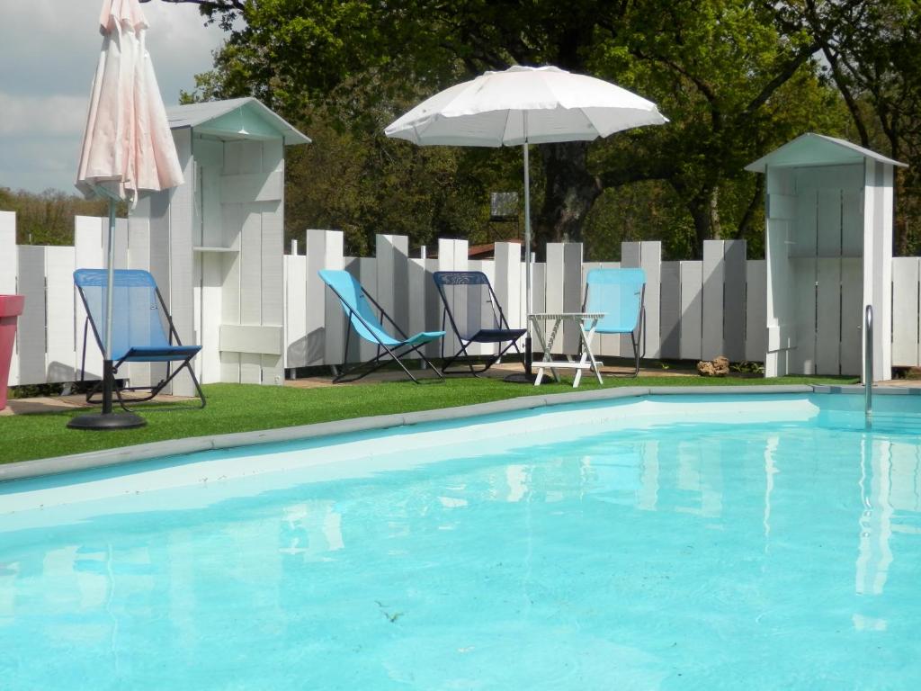 uma piscina com cadeiras e um guarda-sol em La Désirade em Saint-Laurent-de-la-Prée