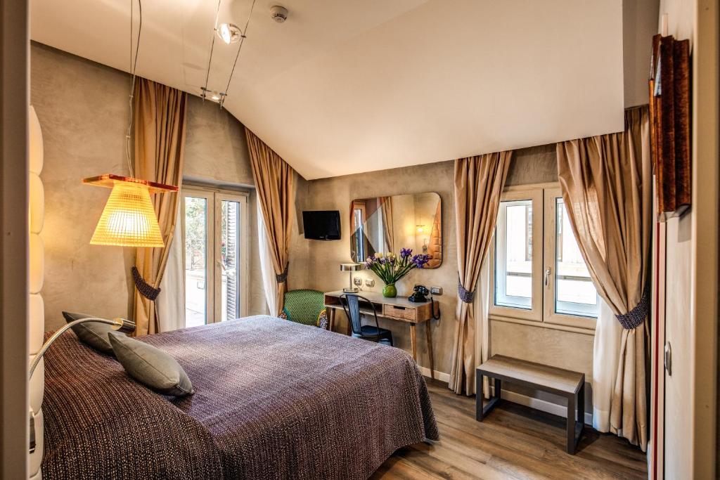 een slaapkamer met een bed, een bureau en ramen bij Parlamento Boutique Hotel in Rome