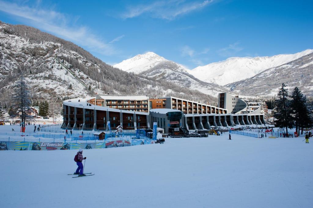 une personne sur un snowboard dans la neige devant un bâtiment dans l'établissement Hotel Rivè - Complesso Turistico Campo Smith, à Bardonnèche