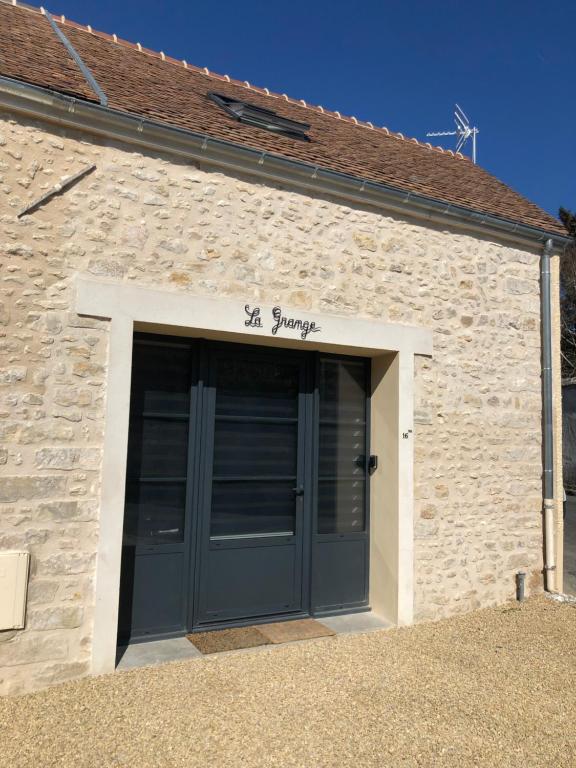 un bâtiment en pierre avec un garage doté d'une porte bleue dans l'établissement La Grange, à Ury