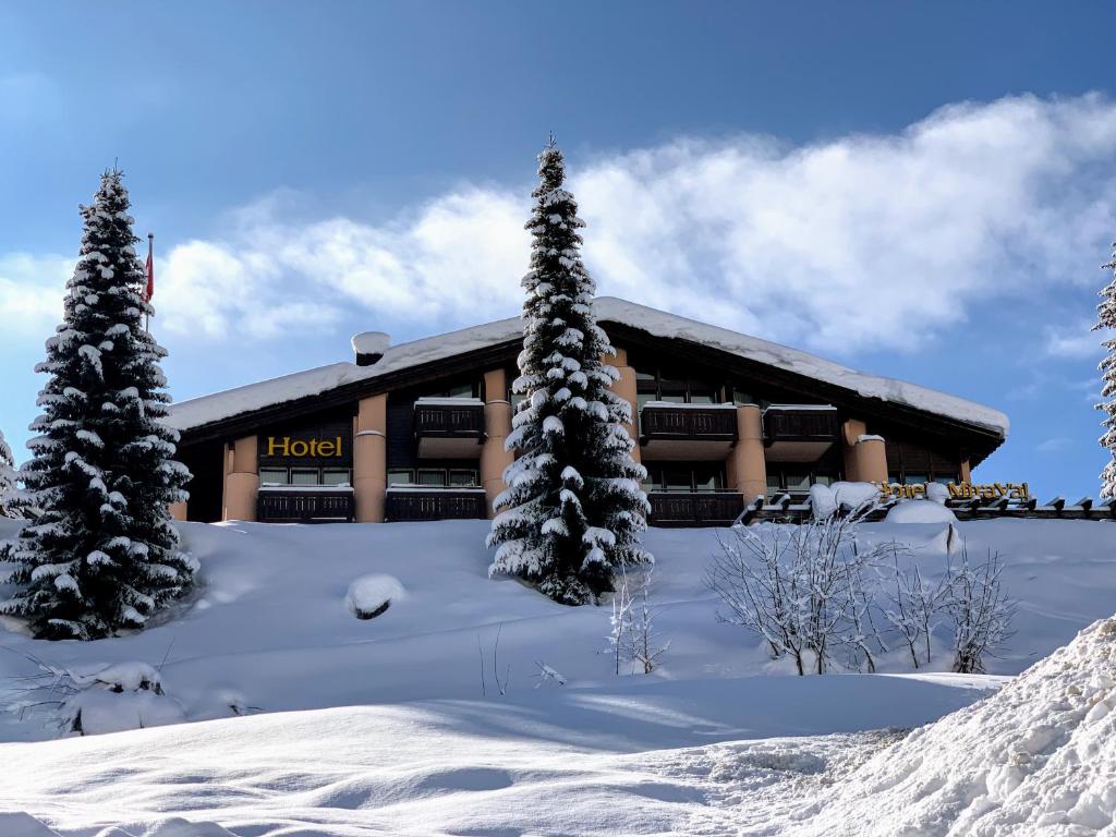 a hotel in the snow with trees in front at T3 Hotel Mira Val in Flims