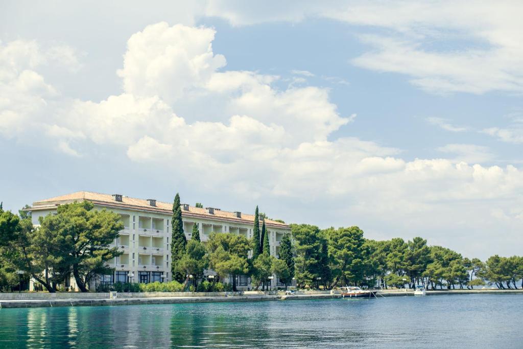 a building next to a body of water at Brijuni Rooms Karmen in Fažana