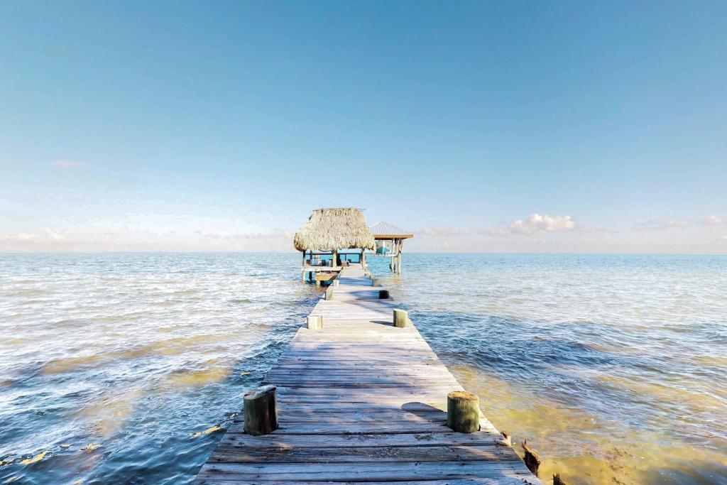 a wooden pier in the ocean with a thatch roof at Casa Edie in Riversdale