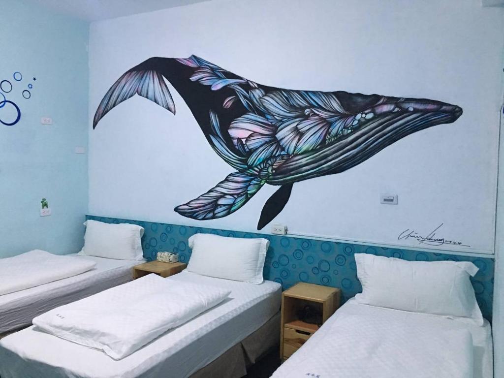 a room with two beds and a dolphin painting on the wall at Light Blue Hostel in Hengchun South Gate