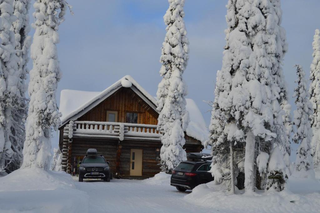 a log cabin in the snow with cars parked in front at Rukajärven Kelopirtit Cottages in Ruka