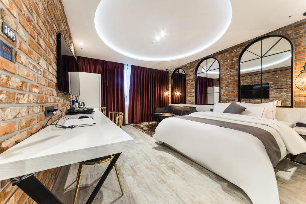 Astro Hotel في يونغين: غرفة نوم بسرير وجدار من الطوب