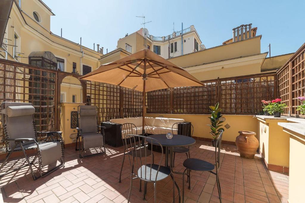 a patio with a table and chairs and an umbrella at Vatican Luxury Terrace in Rome