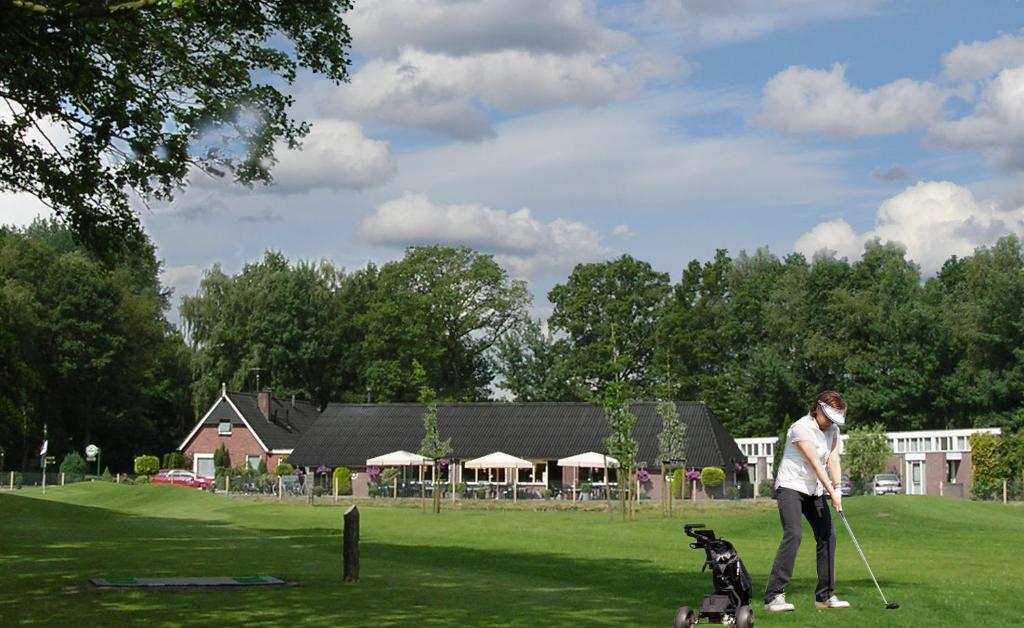 a woman playing golf with a dog on a field at Hotel & Restaurant 'T Holt in Diepenheim