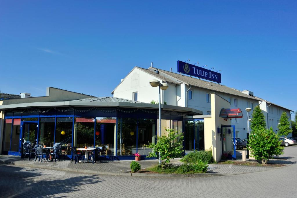 een gebouw met een tafel ervoor bij Plaza Inn Berlin Süd Ludwigsfelde in Ludwigsfelde