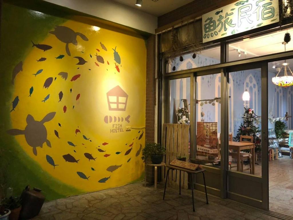 a store with a yellow wall with leaves on it at Fish Hostel in Yingge