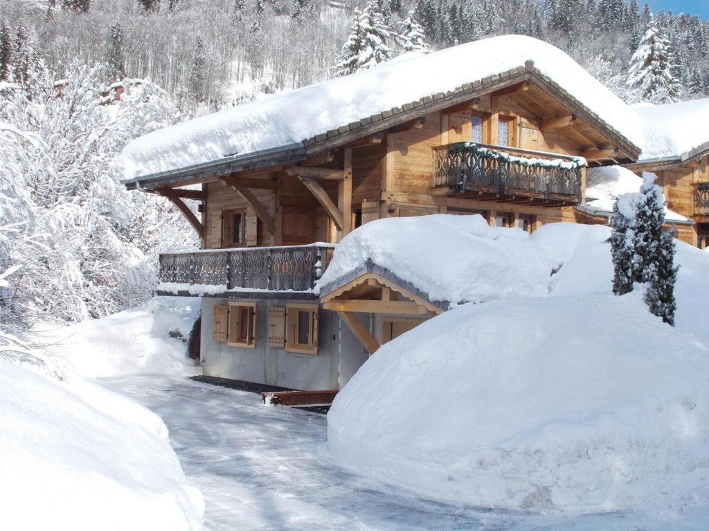 a log cabin in the snow with a pile of snow at Chalet Jonquille in Les Gets