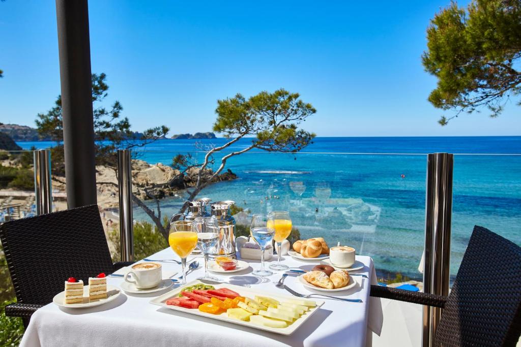 a table with food and a view of the ocean at Universal Hotel Lido Park in Paguera