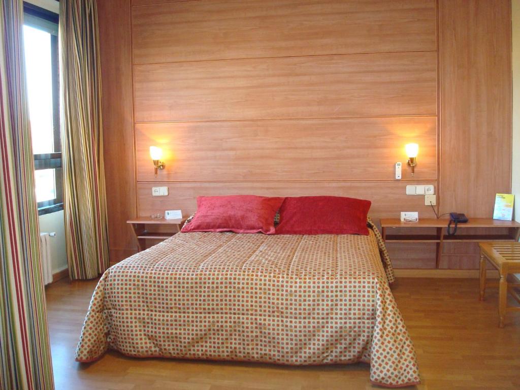 a bedroom with a bed with two red pillows at Hotel Castilla in Albacete