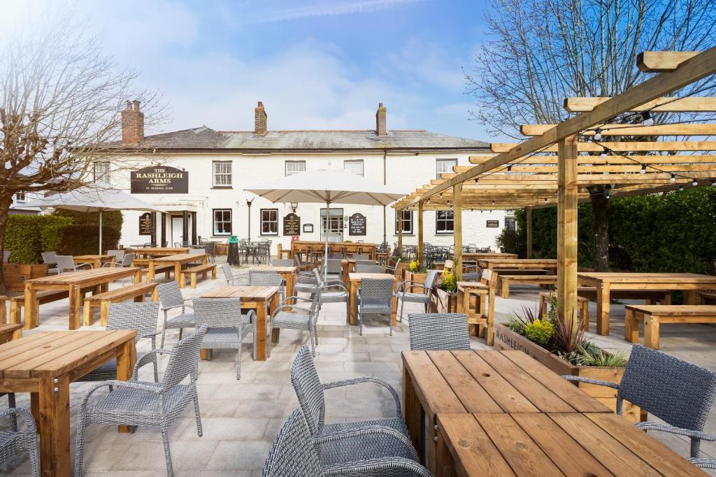 een patio met houten tafels en stoelen en een gebouw bij Rashleigh Arms in St Austell