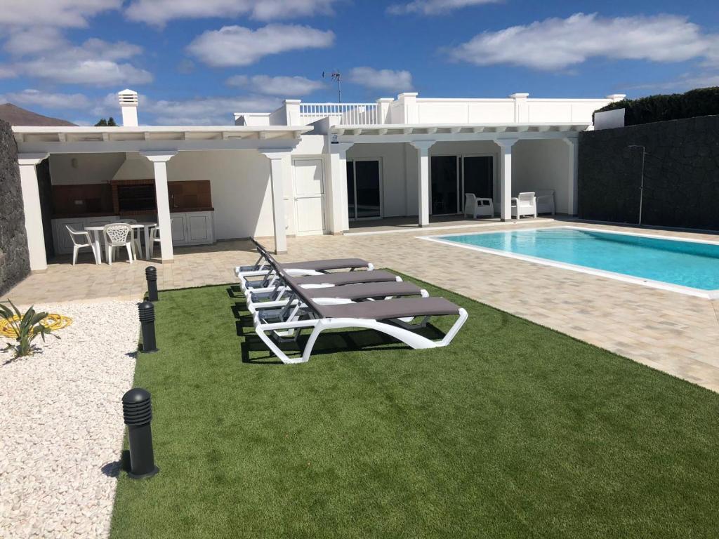 une villa avec une piscine et des chaises longues dans l'établissement Casa Mercedes, à Playa Blanca