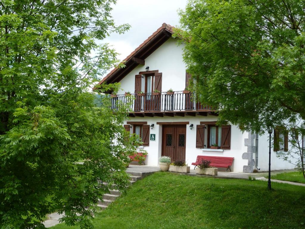 a white house with a red bench in the yard at HOSTAL MENDILATZ in Orbaiceta