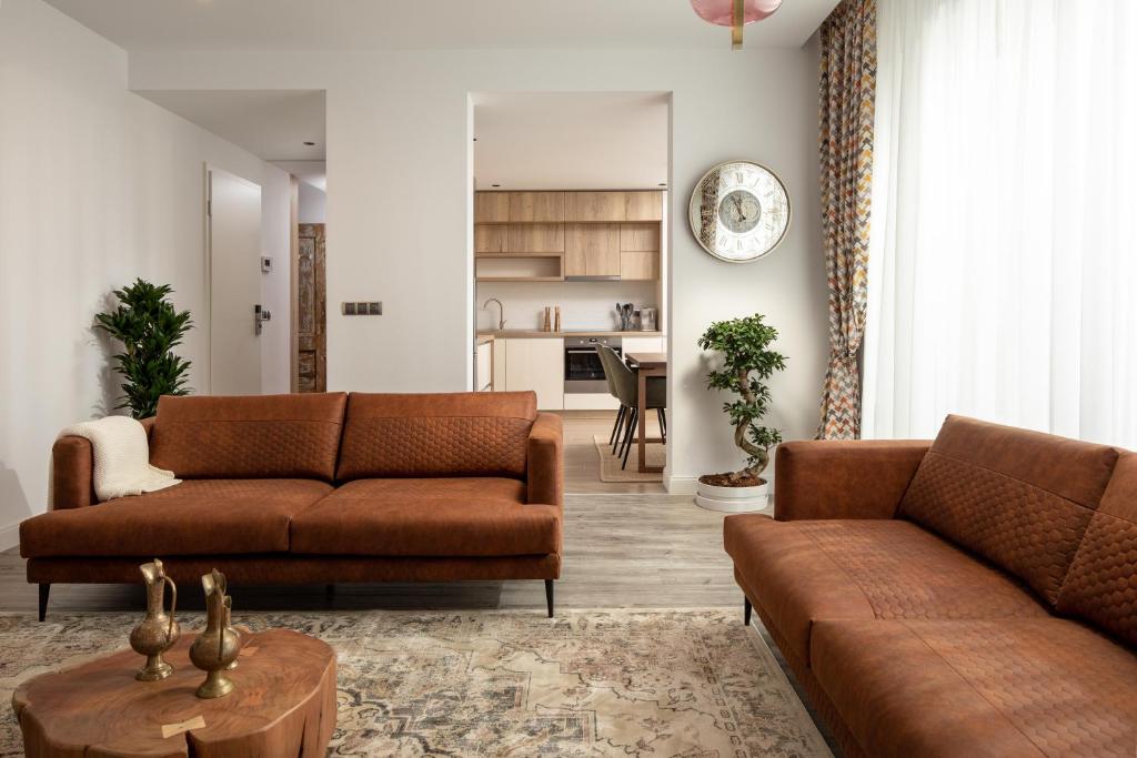 ein Wohnzimmer mit zwei braunen Sofas und einer Küche in der Unterkunft Kanopian Penthouse Brasov in Braşov