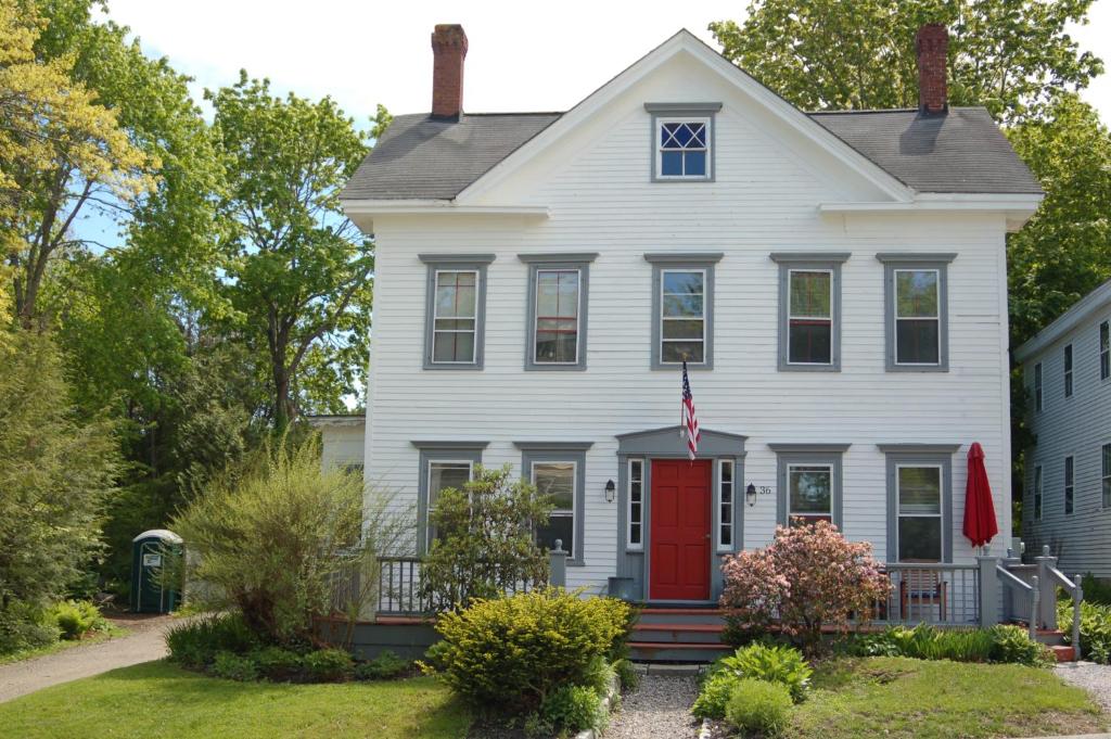 a white house with a red door at 36 Main Apartments in Castine