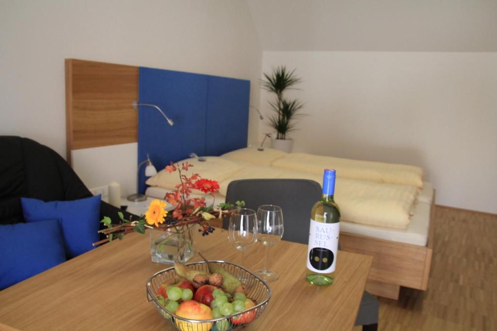 Zimmer mit einem Tisch, einer Flasche Wein und einer Schale Obst in der Unterkunft Hotel Eisenhuthaus in Poysdorf