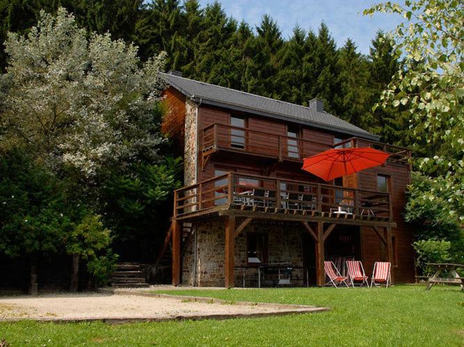 een huis met stoelen en een paraplu ervoor bij Duplex Chalet in Rendeux Ardennes with Sauna and Terrace in Verpré