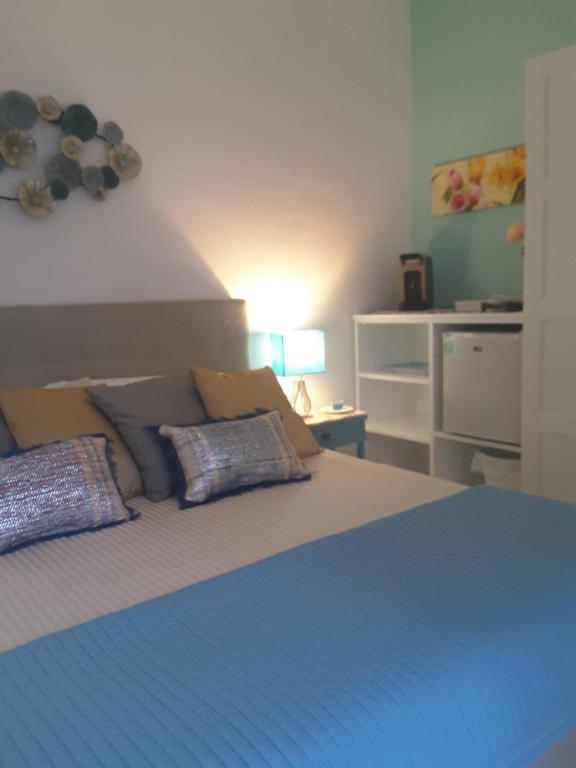 una camera da letto con un grande letto con lenzuola e cuscini blu di Trame - Poesia Di Mare a Polignano a Mare