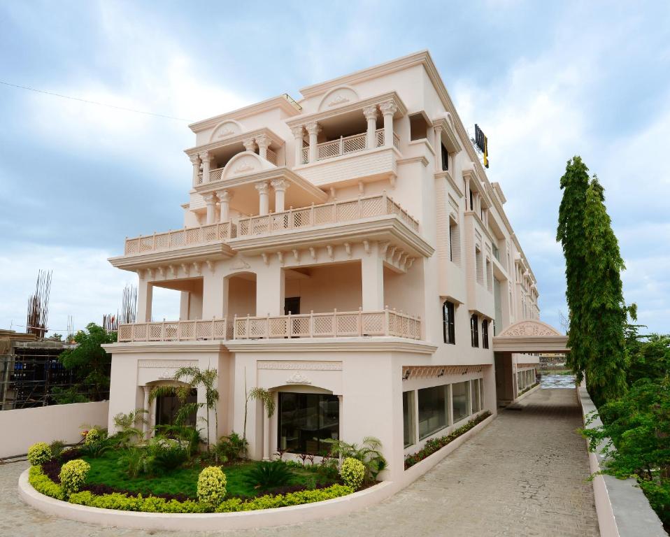 Großes weißes Gebäude mit Balkon in der Unterkunft JC Castle in Shirdi