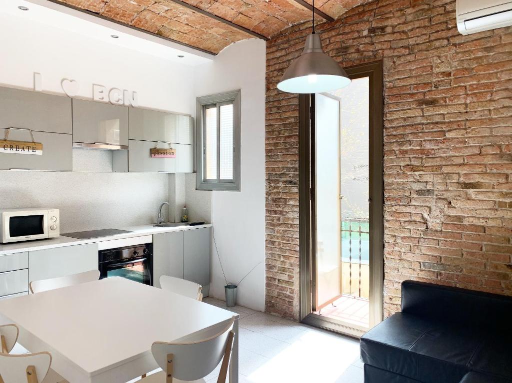 a kitchen with a white table and a brick wall at Charm Miró in Barcelona
