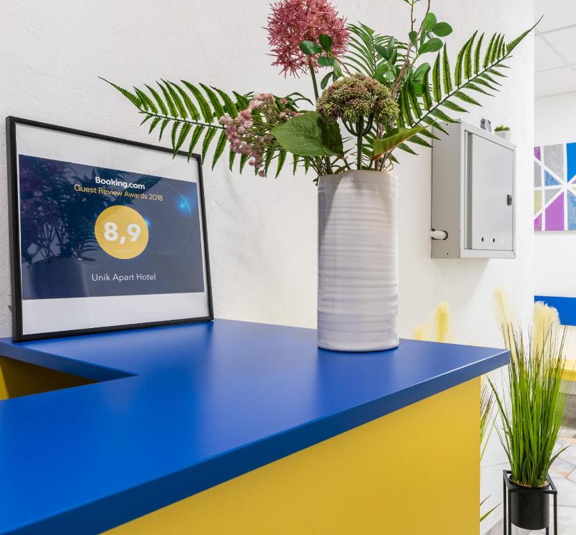a blue and yellow desk with a vase with flowers at Unik Apart in Kyiv