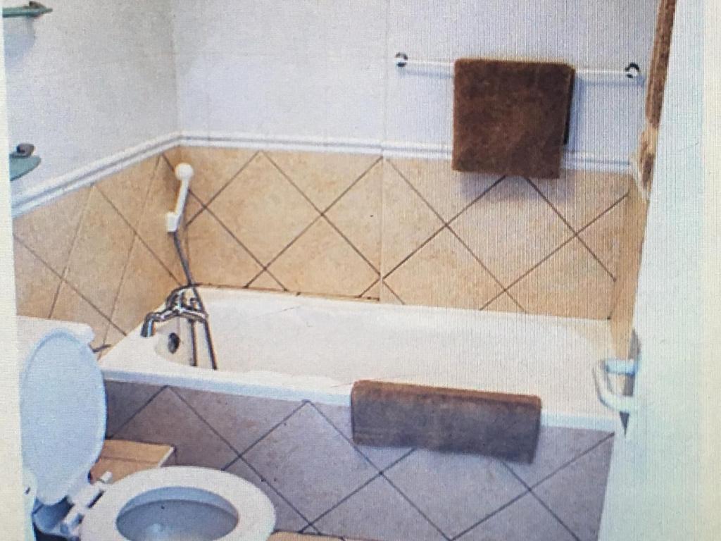 a bathroom with a toilet and a bath tub at Ocean View B1001 in Bloubergstrand