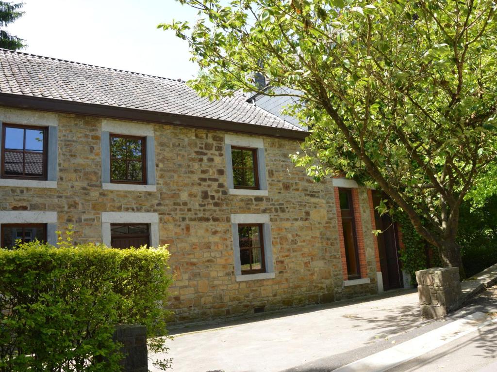 een stenen huis met een boom ervoor bij This plain house is very suitable for groups in Ferrières