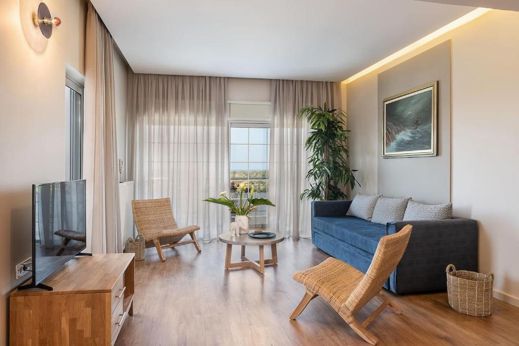 a living room with a blue couch and a tv at Anemone Holiday Apartment in Kato Daratso