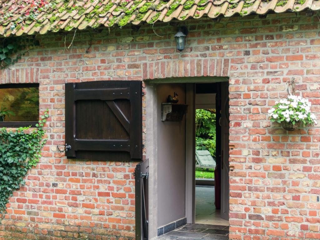 an open door of a brick building with a window at This accommodation is full of atmosphere and on a beautiful estate in Zedelgem