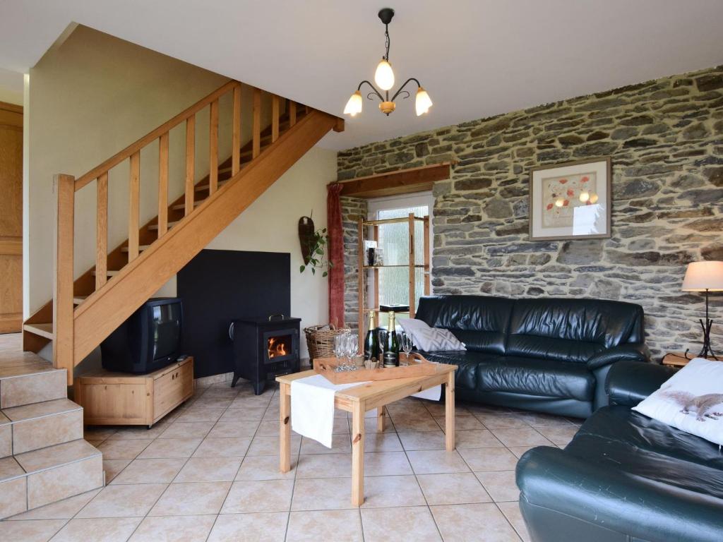 sala de estar con sofá de cuero negro y pared de piedra en Comfortable Cottage in Neufmoulin with Meadow View, en Houffalize
