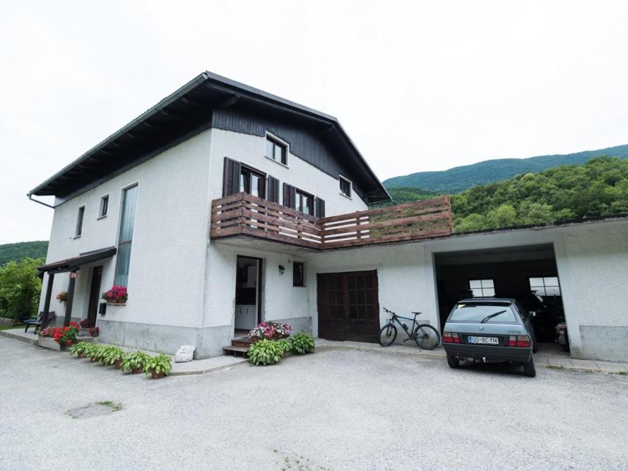 a white house with a car parked in front of it at Apartma Matajurc in Trnovo ob Soči