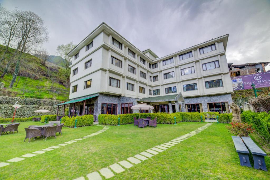 a large white building with a lawn in front of it at Rock Manali by Vivaan in Manāli